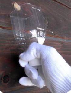 壁板についているベージュ色のものと、半分に切ったペットボトルを持った白い手袋をした手が写っている写真