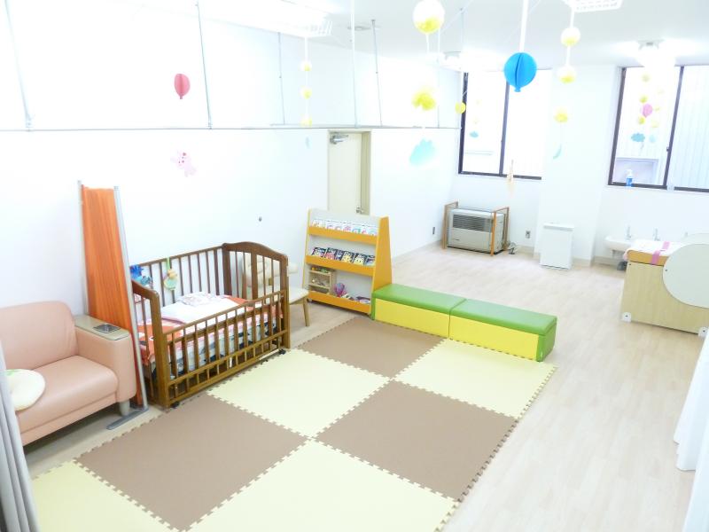 ベビーベッドや本棚、ソファなどが設置された部屋の写真