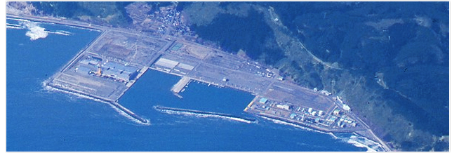 真後ろに山がある海沿いの工場地帯の航空写真