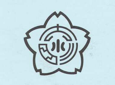 水色を背景に黒で桜の花の中心に漢字で小と書かれた校章のイラスト