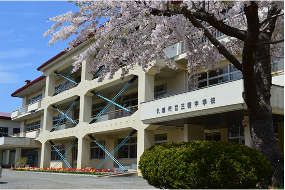 昇降口横に大きな桜の植えられた、「久慈市立三崎中学校」と書かれた3階建て校舎の写真