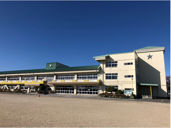 緑色の屋根の校舎と校庭の写真