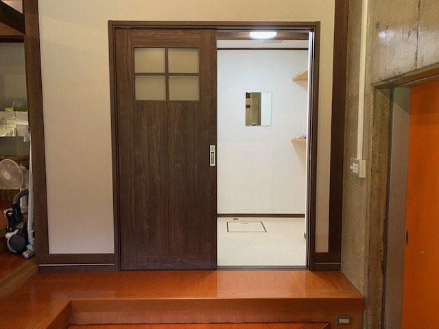 木目調のスライドドアの奥に白い床と壁の部屋が見える写真
