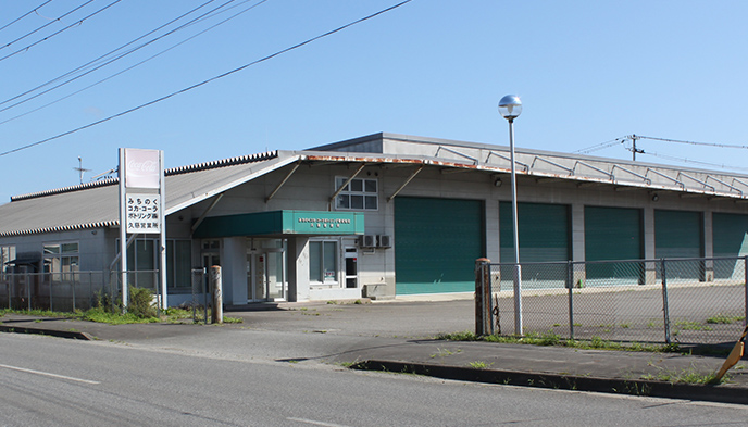 企業施設の入り口の写真 緑色のシャッターが閉まっている