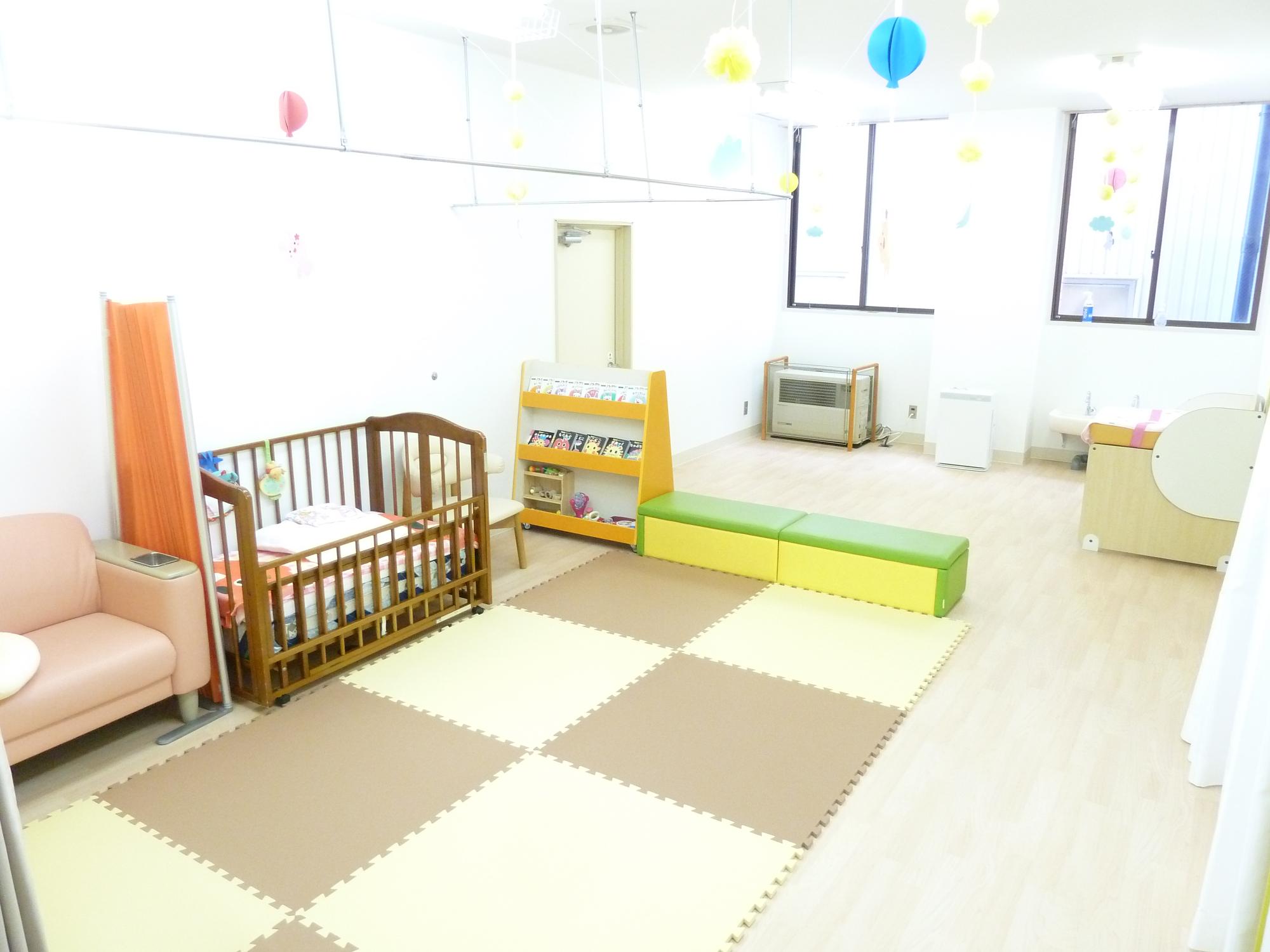子ども用ベッドや絵本棚、カラフルなソファやマットが設置された明るい印象の室内の写真