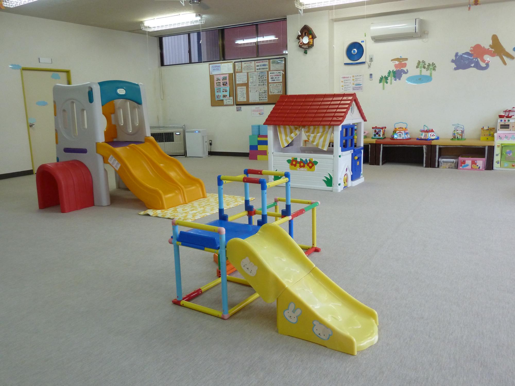 小さな滑り台やアスレチックなどの遊具が置かれた、広い部屋内の写真
