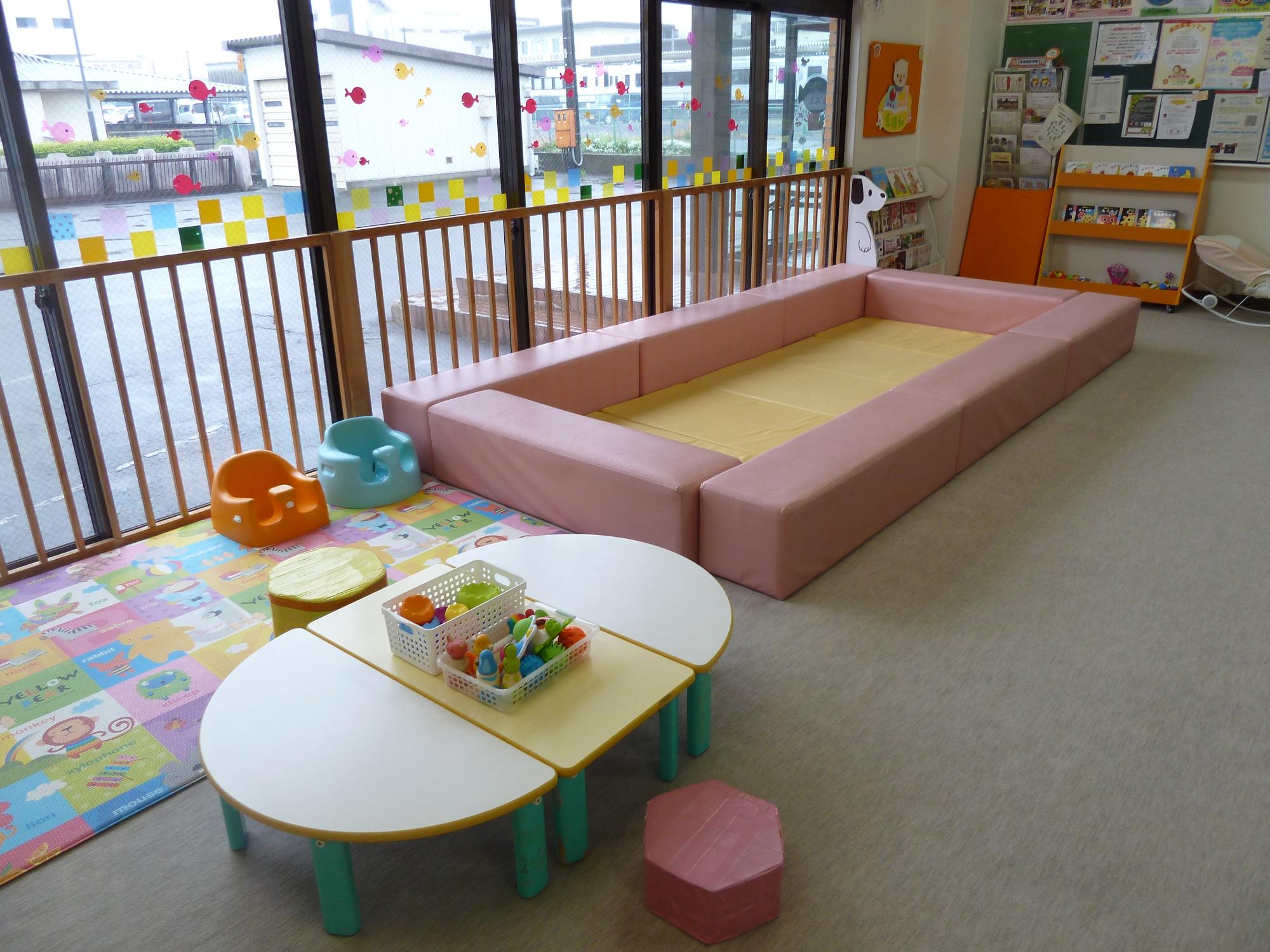 子ども用の背の低い椅子やソファ、玩具の入ったカゴが乗った机などが設置されている室内の写真