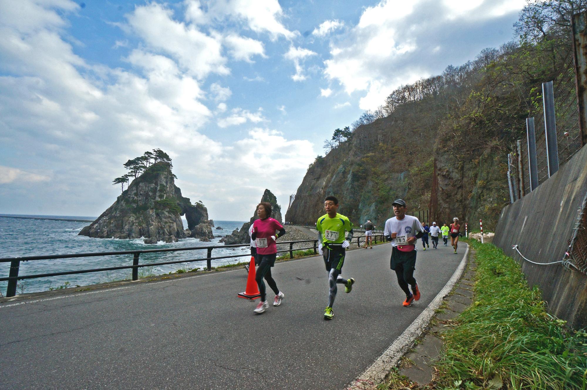 海岸のそばにある道路を走っている人たちの写真