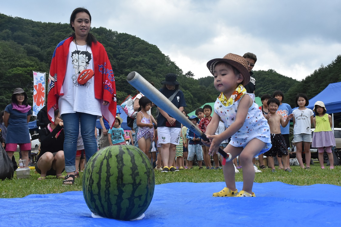 ブルーシートの上で子供がバットを持ってスイカ割りをしようとしている写真