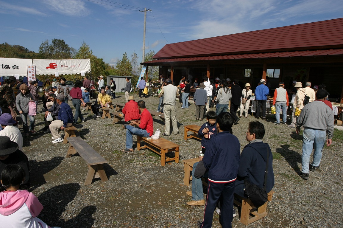 背の低い長椅子が置かれた広場に集まっている人たちの写真