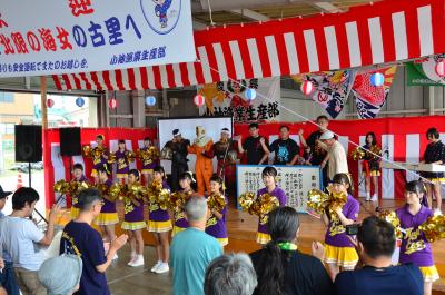 紅白の幕を背景に演奏やダンスをしている人たちの写真