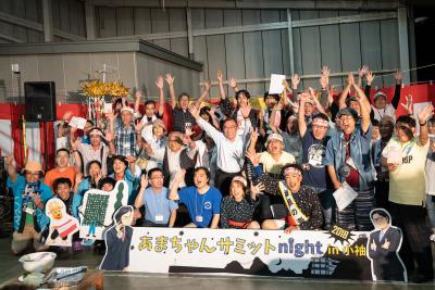 紅白の幕を背景に手を挙げている人たちの写真