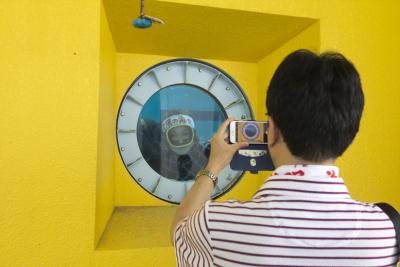 潜水艇の窓を模したものの向こうにいる海女さんを撮影している人の写真