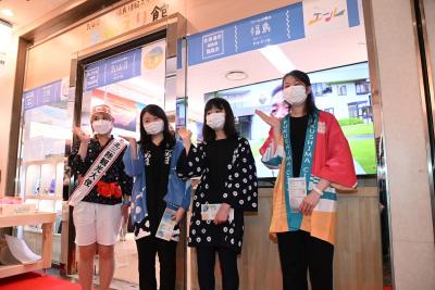 店の前で女性4人が片手を上げながら横一列に並んでいる写真