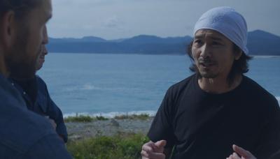 頭にタオルを巻いた人と手前の男性が話をしている写真