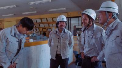 ヘルメットをかぶった3人に向かってお辞儀をしている男性の写真