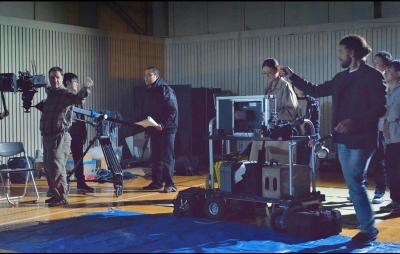 青のビニールシートの上に載せた機材の周りで話し合っている人たちの写真