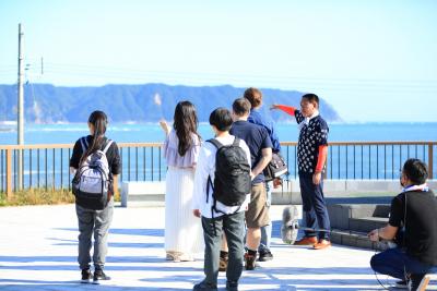 海辺の広場から遠くの島を指さしている人たちの写真