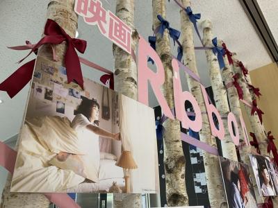 木が何本も並んでおり写真の展示と共にリボンが括り付けられている写真