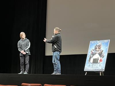 映画の上映会のステージで男性2人が立ち話をしている写真