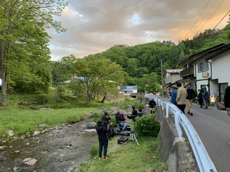 道路脇の河川敷でカメラを構え撮影を行っている写真