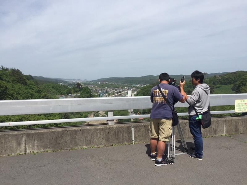 街を見下ろせる高台で男性2人が町並みを撮影している写真