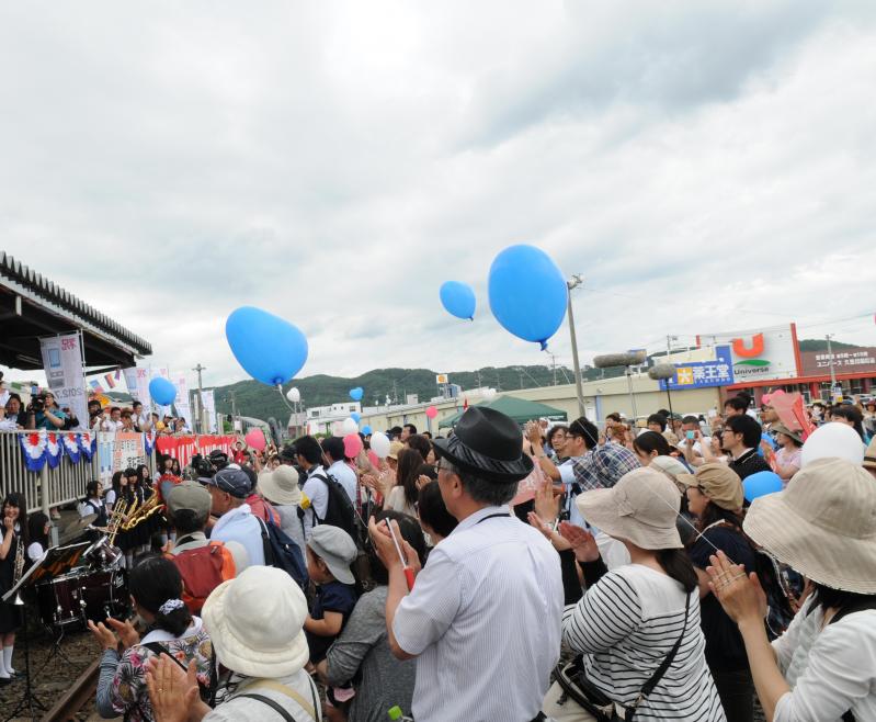 広場に集まった人たちの一部が水色の風船を持っている写真