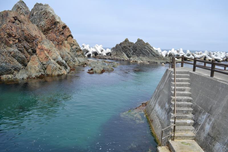 防波堤に付けられた階段が海とつながっている写真