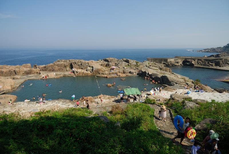 岩場を削って作られたプールで人々が泳いでいる写真