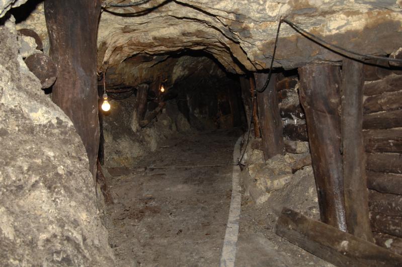 木の支えや電球が吊るされた坑道の写真