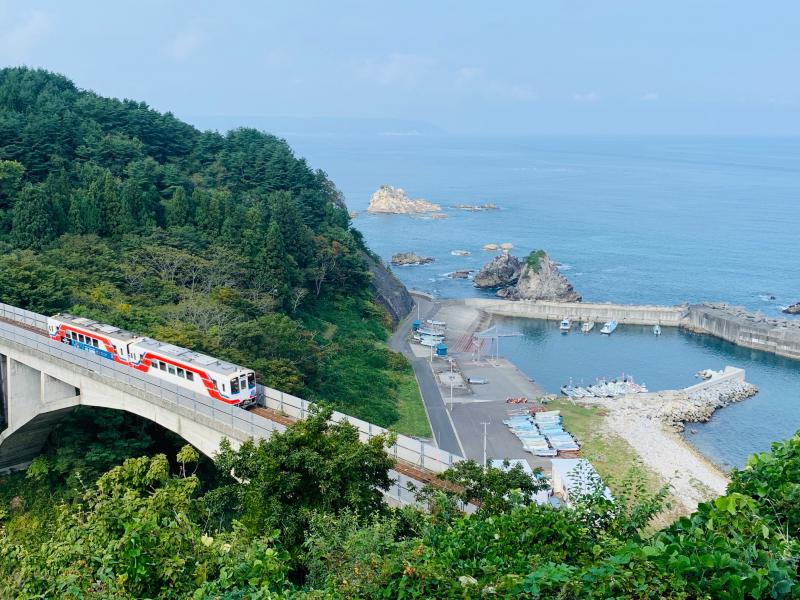 海の近くに設置された線路に電車が走っている写真