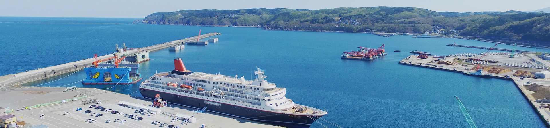 人工の岬に白い船が停泊している写真