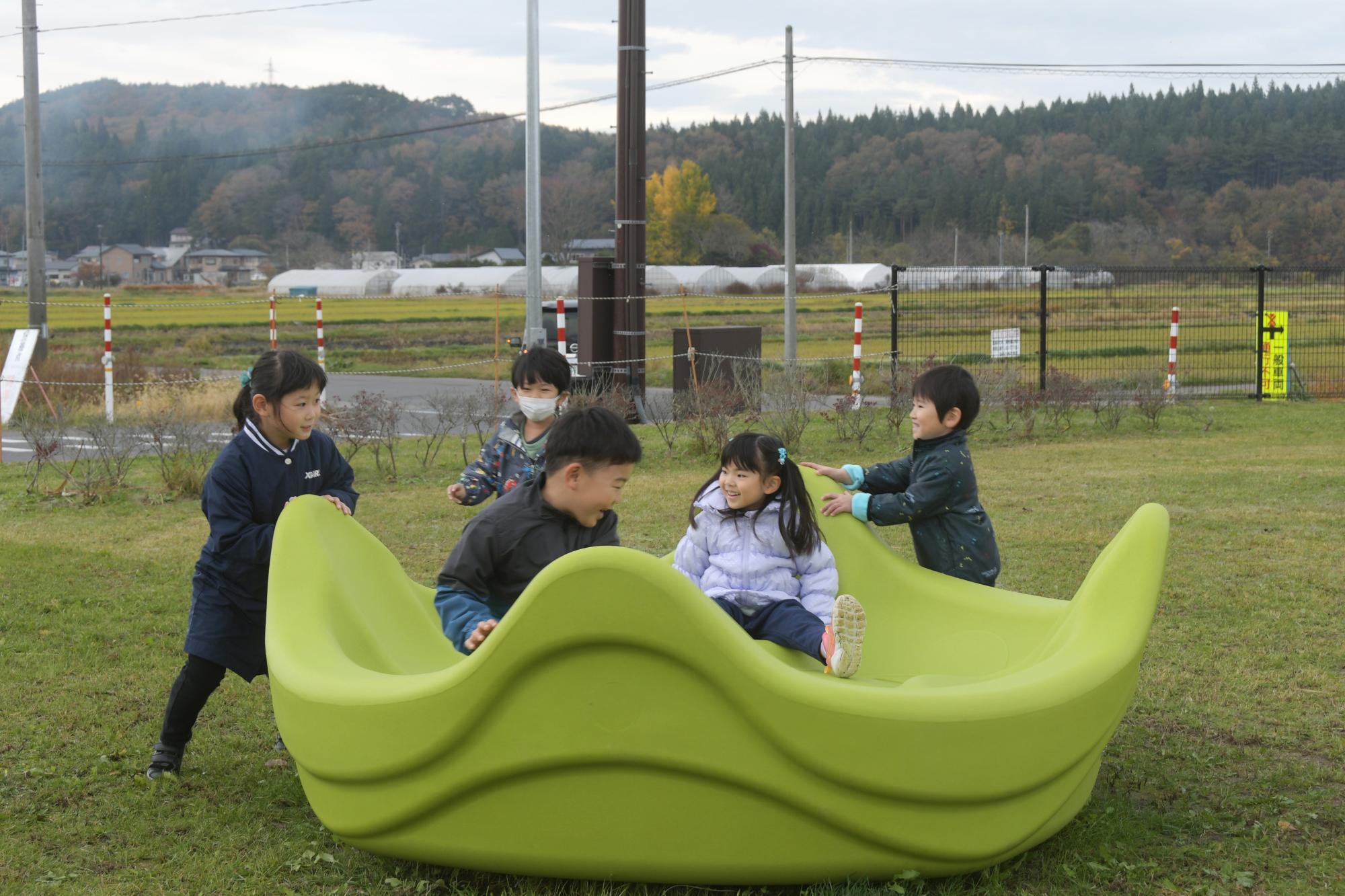 5人の子供が緑色の遊具で遊んでいる写真