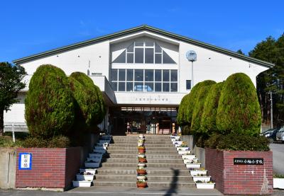 両脇にお花と低木の植えられた階段の先に「久慈市立小袖小学校」と書かれた校舎が建っている写真