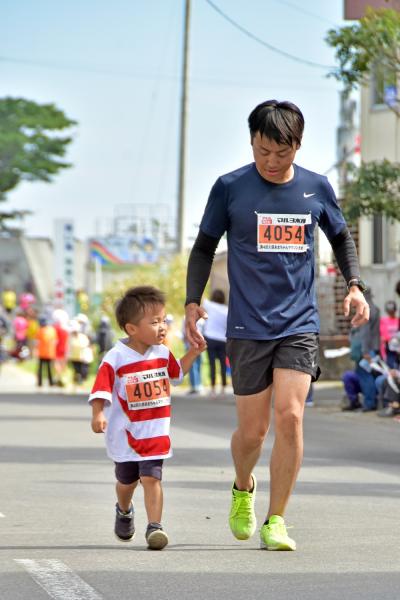 男性と子供が手を繋ぎながら一緒に走っている写真
