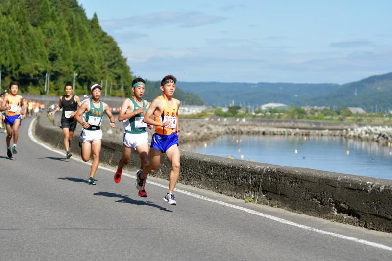 マラソンランナーが海沿いの道路を走っている写真