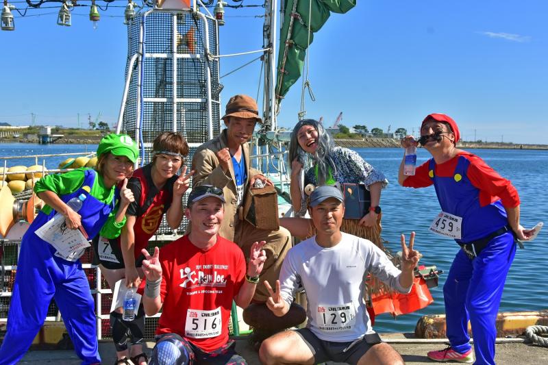 ポーズをとっているキャラクターの格好をした人たちとピースをしているマラソンウェア姿の2人の写真