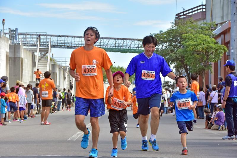 男性と子供のペアの2組が隣同士で一緒に走っている写真