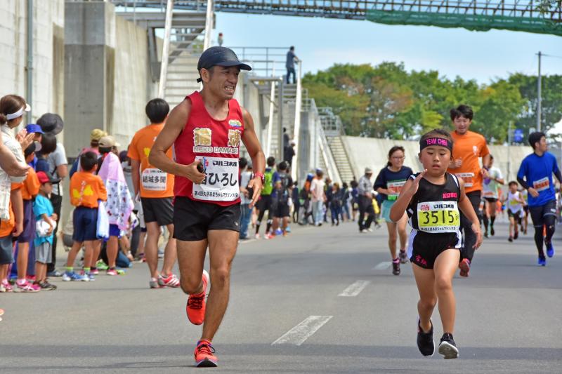 タレントの猫ひろしと女の子がマラソンコースを走っている写真