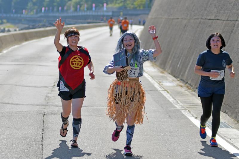 金太郎の格好の女性と浦島太郎の格好の女性が片手を上げながら一緒に走っている写真