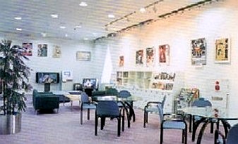 壁にものが飾られており丸テーブルと椅子が設置されている施設の一角の写真