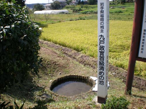 「九戸政実首級清めの池」と標識のある円形の小さな池の写真