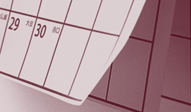 全体を赤く加工されたカレンダーの左下が風でめくれている写真