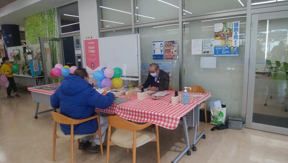 広い館内で大きなテーブルに男性2人が座っている写真