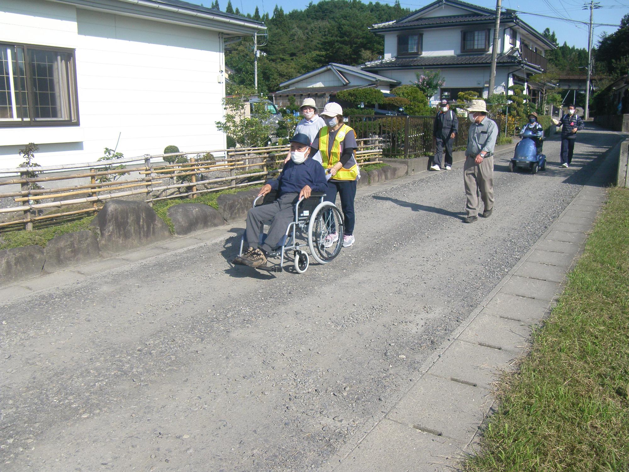 避難行動要支援者の方が乗った車いすを押している写真