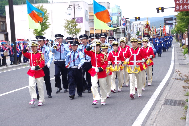 赤い制服の人たちと警察官が道路を行進している写真