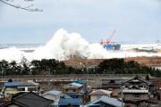 防波堤にぶつかり白い飛沫をあげながら押し寄せる津波の写真