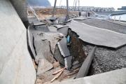 陥没した道路と、それに引っ張られ傾いた建物の外壁の写真