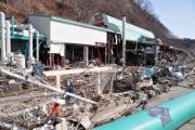 フェンスが壊れ、周囲や中ががれきなどで散乱した建物の写真