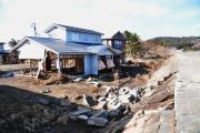 一階部分が破壊され骨組みのみになっている二階建ての建物の写真